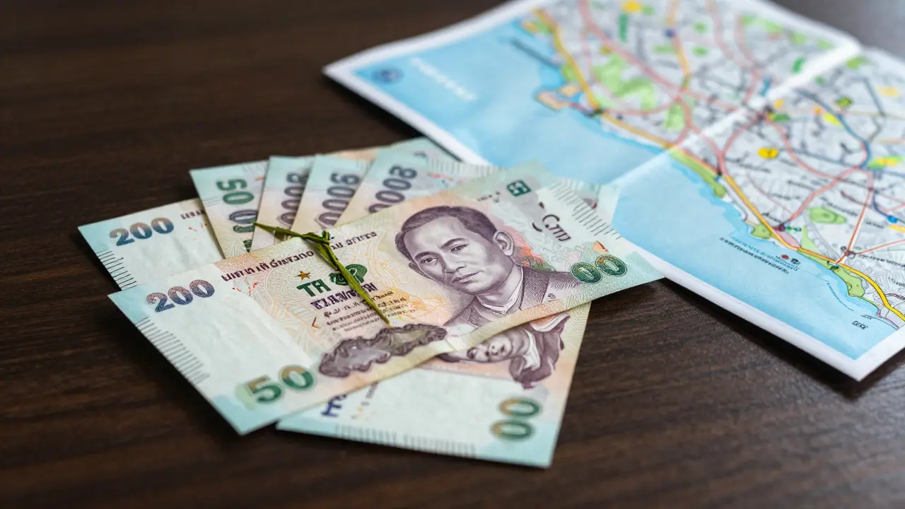 Thai Baht cash and travel map on a dark table
